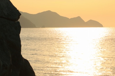 唐尾湾・ばべ鼻付近のリアス式海岸の夕日の絶景写真。海に光の道が出来ている。