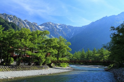 梓川と河童橋、残雪の穂高岳と青空、山肌に朝日の当たる早朝の上高地の絶景写真